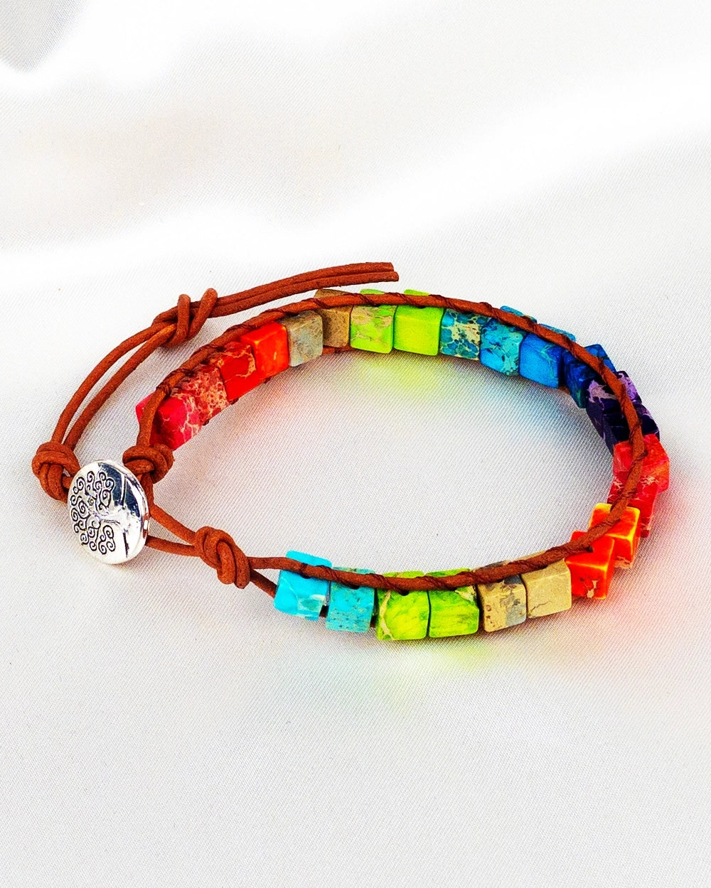 A colorful woven healing bracelet with a bohemian style, featuring a mix of colorful beads and a silver charm.