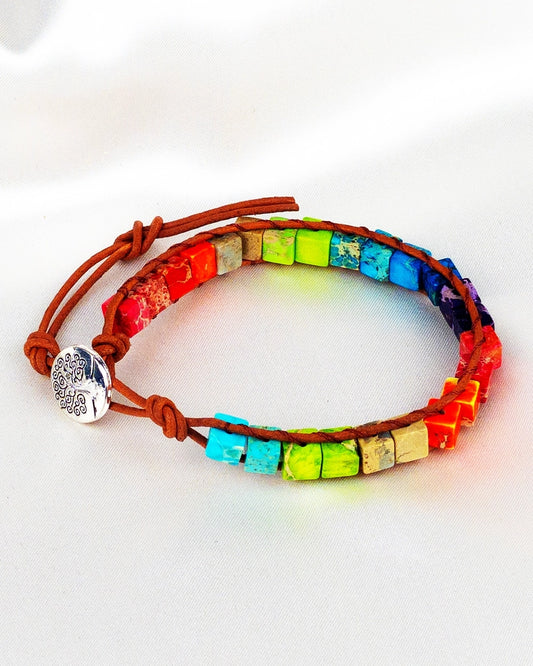 A colorful woven healing bracelet with a bohemian style, featuring a mix of colorful beads and a silver charm.