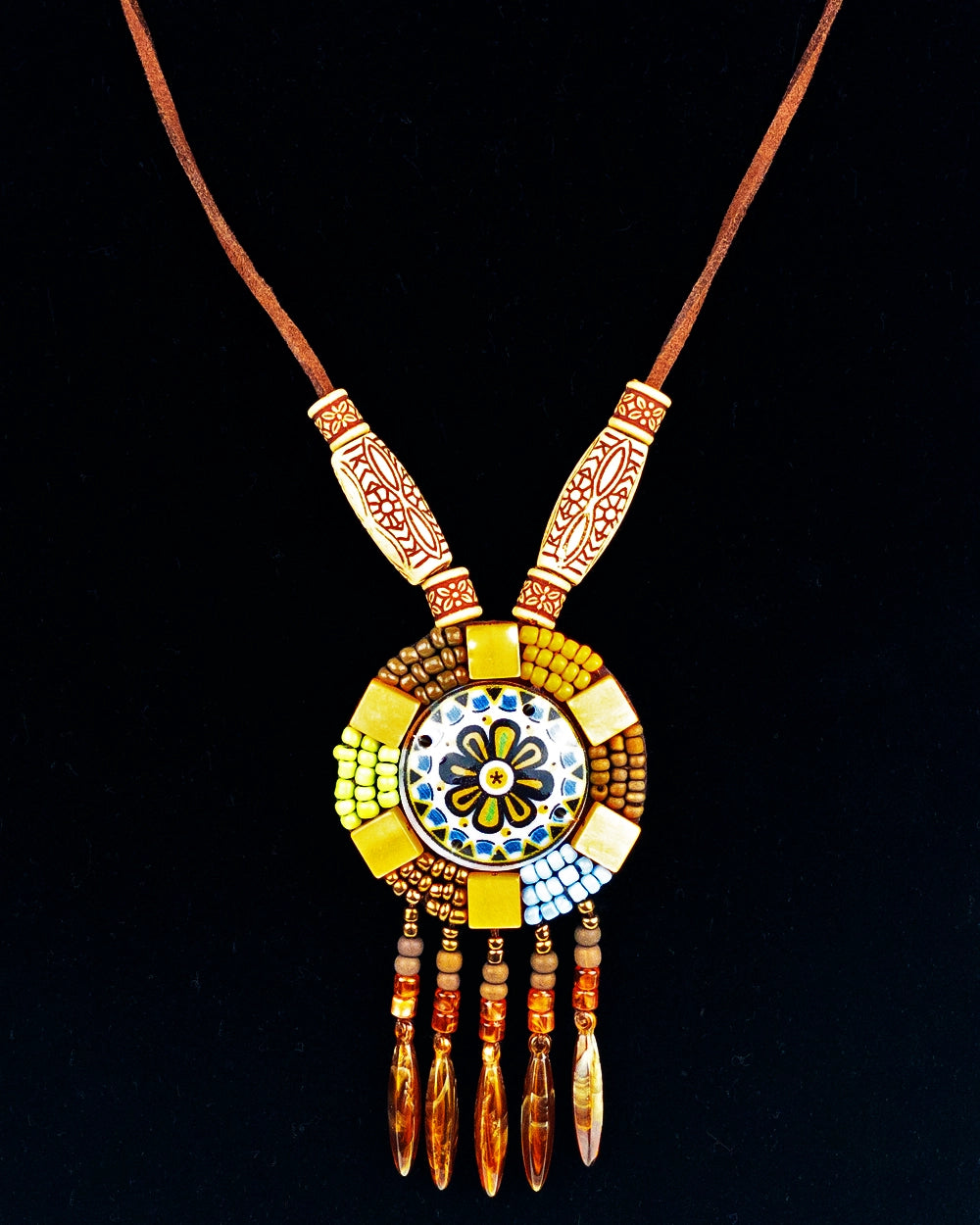 A hand-braided necklace with a round decor tassel charm and a wooden pendant, featuring colorful beads and natural fiber tassels.