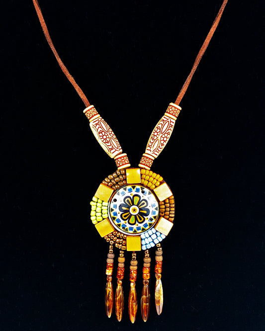 A hand-braided necklace with a round decor tassel charm and a wooden pendant, featuring colorful beads and natural fiber tassels.