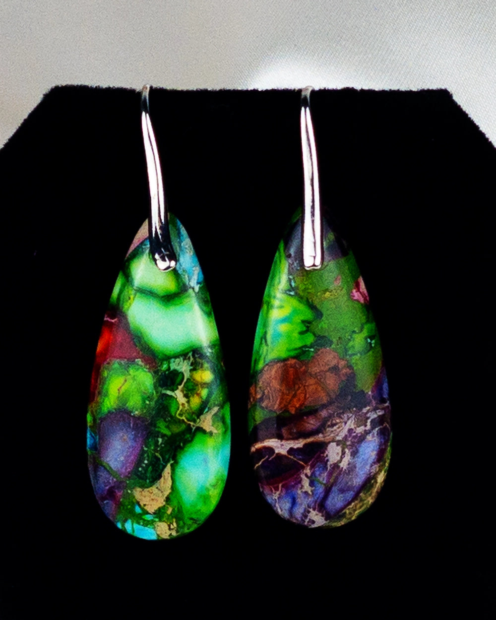 A pair of multicolored beaded earrings with a drop pattern and a metallic hook.