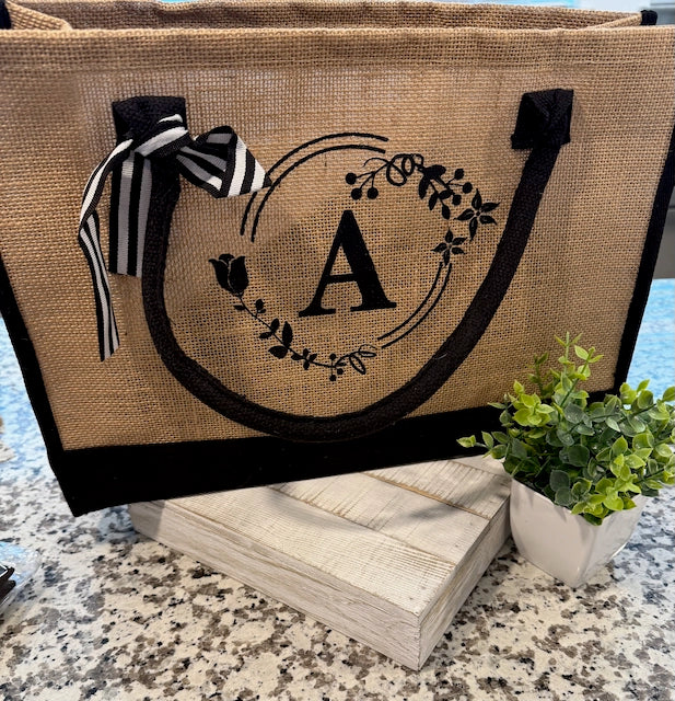 Tote bag with monogram 'A' and decorative elements on a stone surface.
