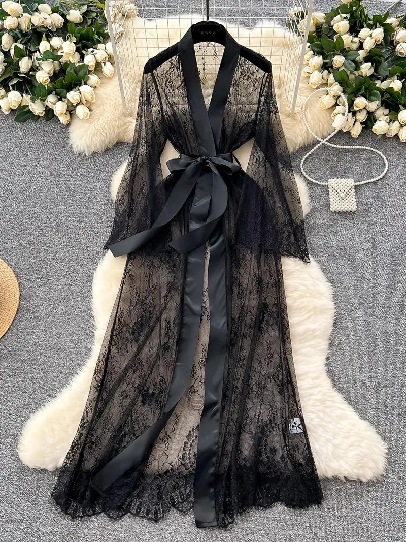 Black lace robe with satin ribbon on a white fur surface with floral decorations.